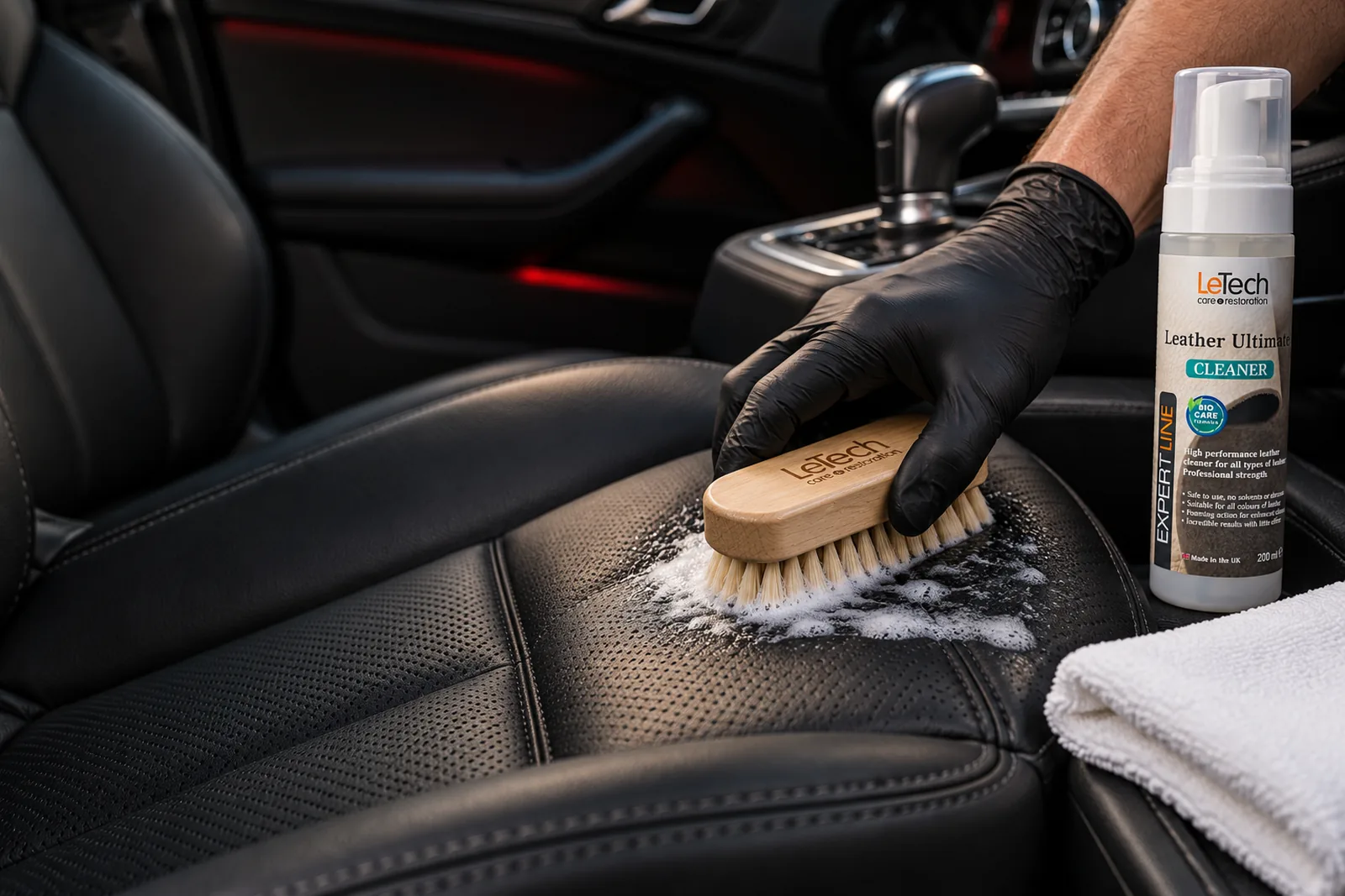 Ilustračný vizuál: čistenie čiernej koženej sedačky auta drevenou kefkou LeTech a penou Leather Ultimate Cleaner